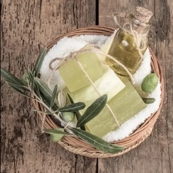 A basket of soap and olive oil on top of the table.