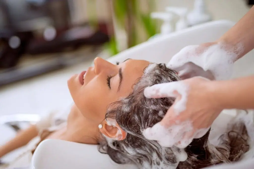 A woman is washing her hair in the bathtub