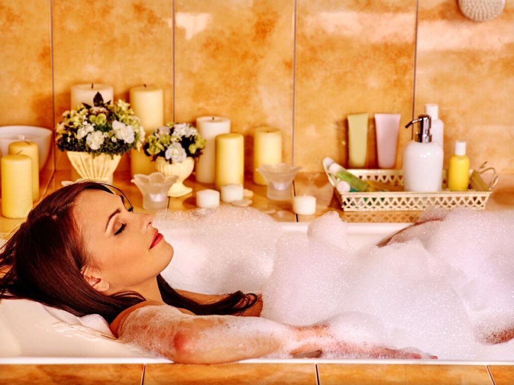 A woman laying in the bathtub with foam on her body.